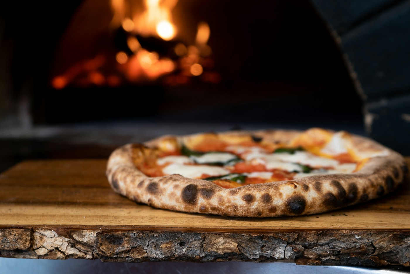 Pizza artesanal diante de um forno a lenha